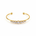ALIÉA Celeste armbånd i 18K guldbelagt rustfrit stål med funklende zirkonia-sten i et elegant, åbent design.