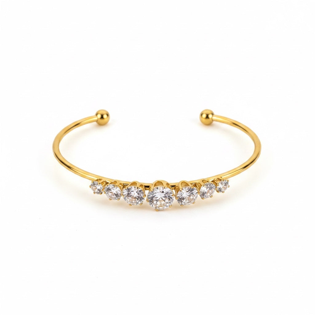ALIÉA Celeste armbånd i 18K guldbelagt rustfrit stål med funklende zirkonia-sten i et elegant, åbent design.