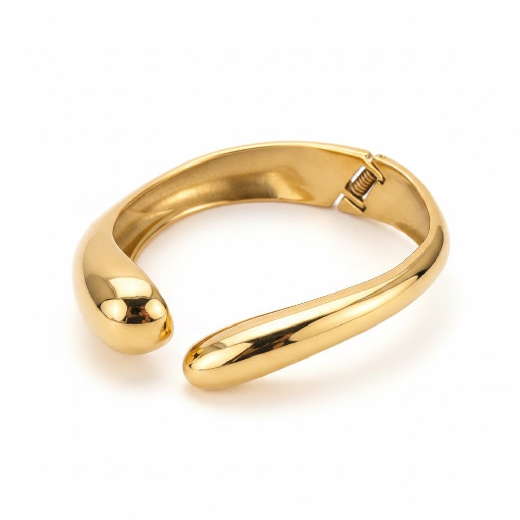 ALIÉA Helena armbånd i 18K guldbelagt rustfrit stål med et skulpturelt, organisk og blankt design.