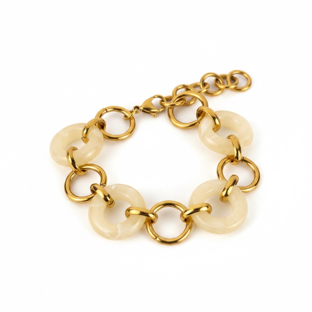 ALIÉA Olivia armbånd i 18K guldbelagt rustfrit stål med elegante ivoryfarvede resin-ringe i et moderne design.